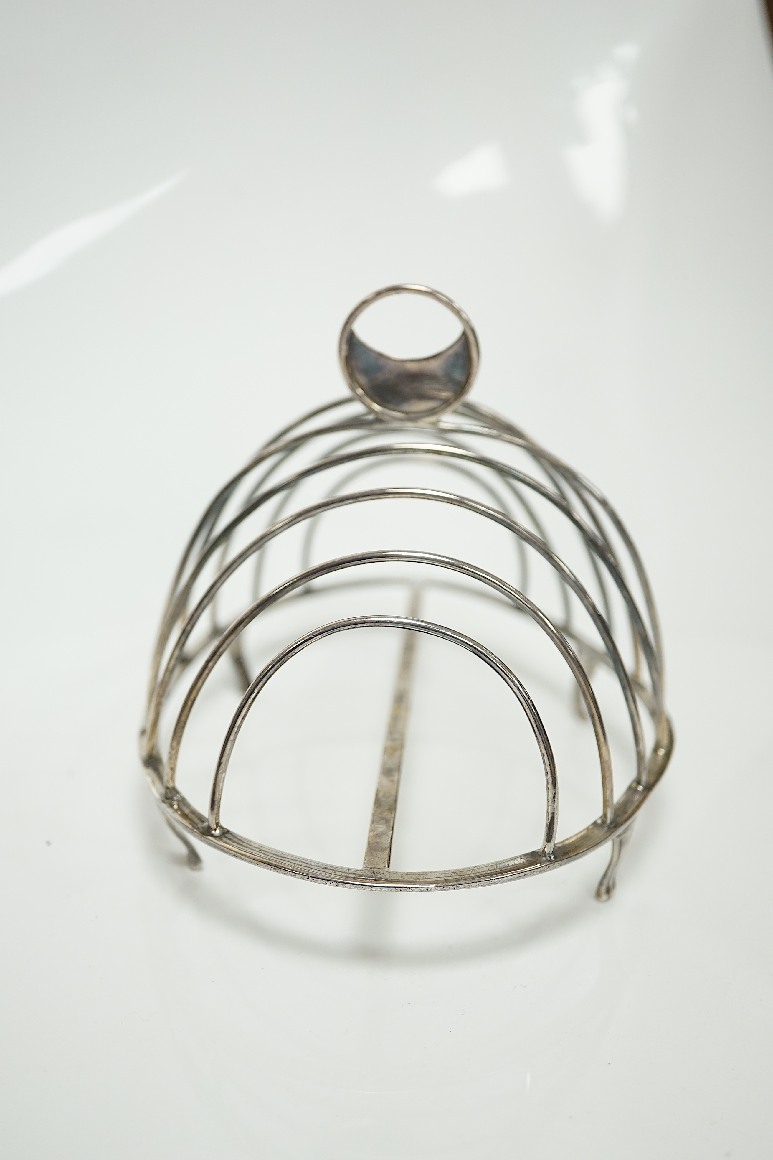 A George III silver oval nine bar toast rack by Robert & Samuel Hennell, with crescent ring handle, on four tapering feet, London, 1803, length 18.4cm. Condition - poor to fair